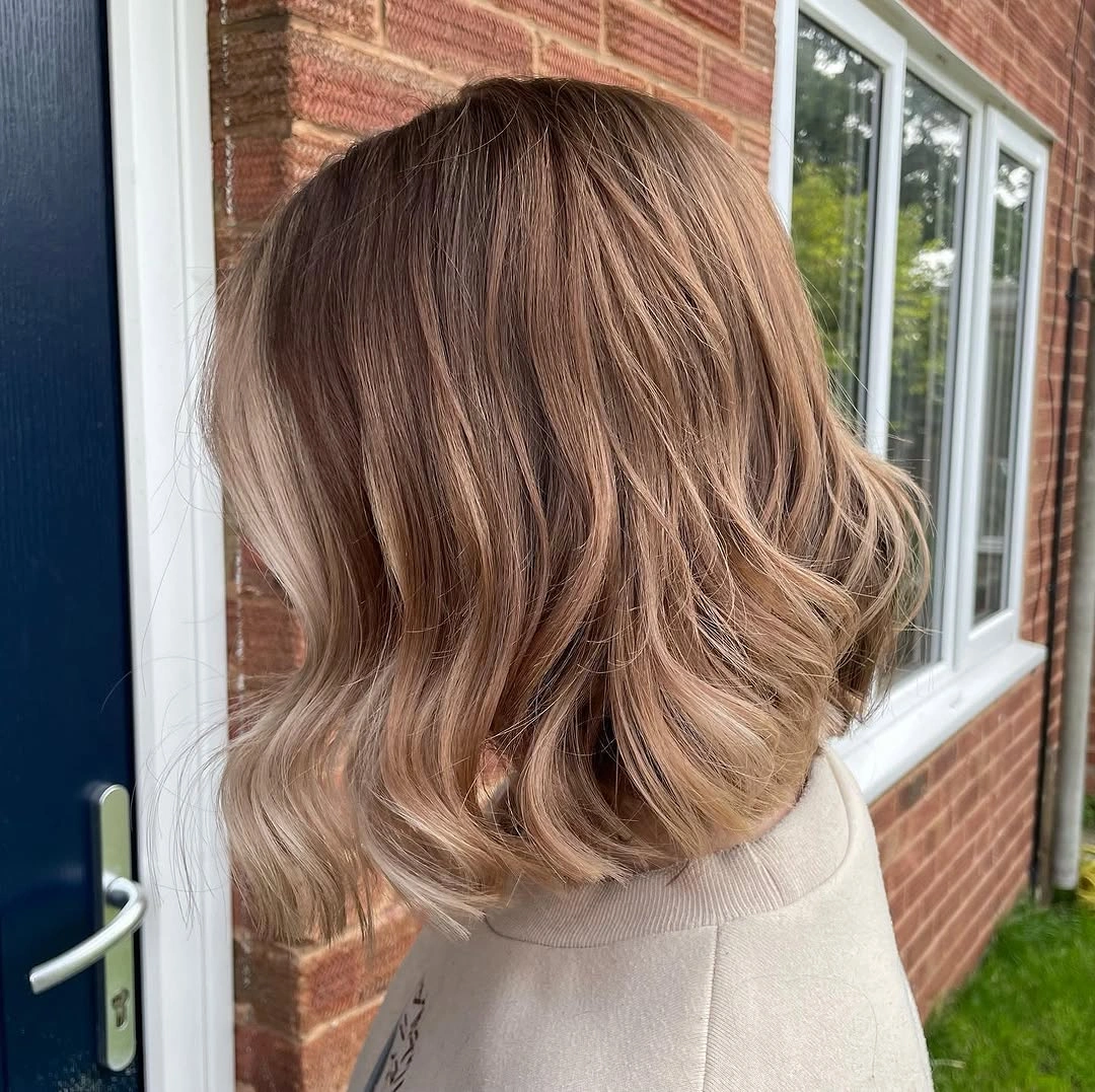 Short wavy beige-blonde lob with slightly deeper taupe roots