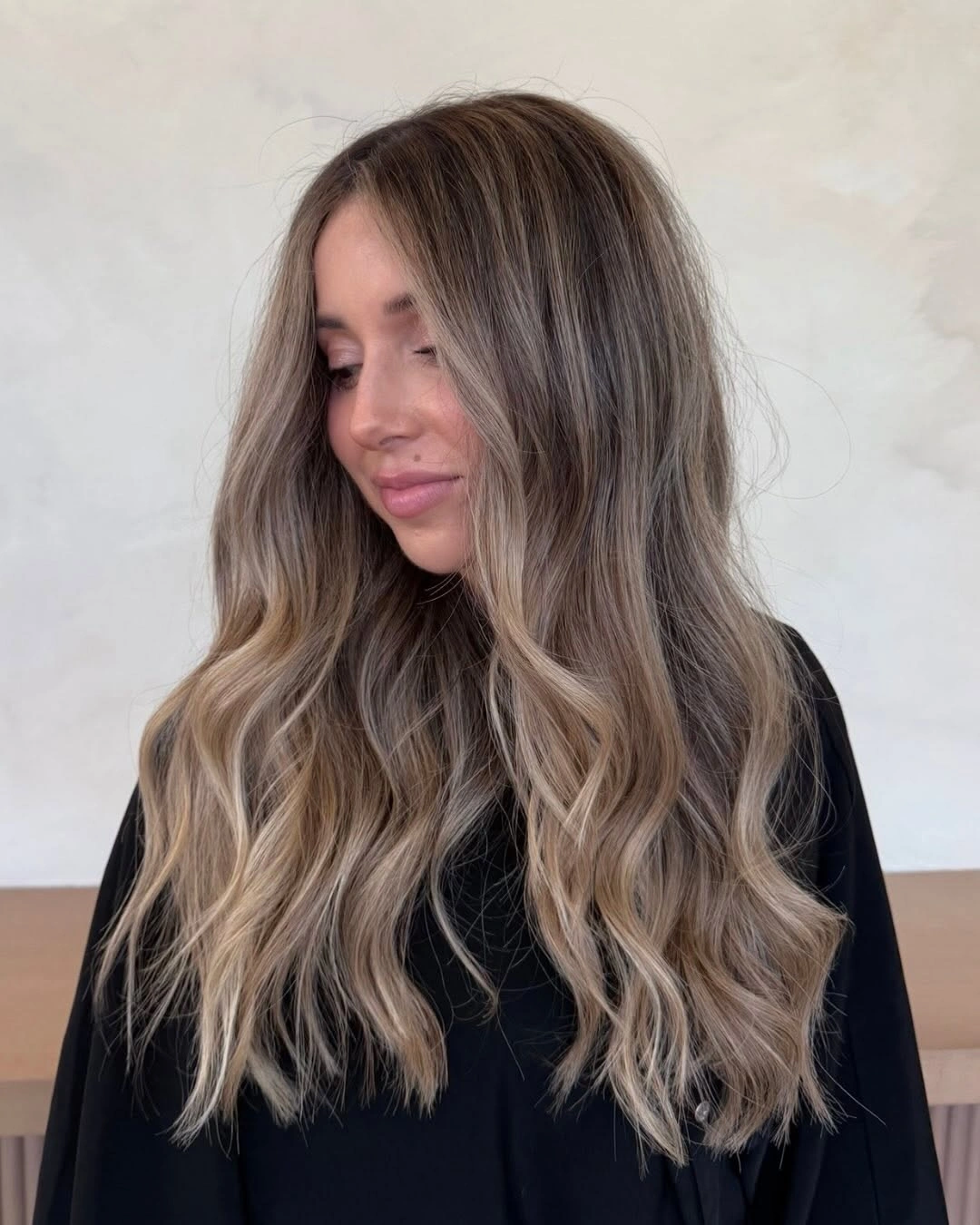 Long waves shifting from dark brunette roots to ash-blonde lengths