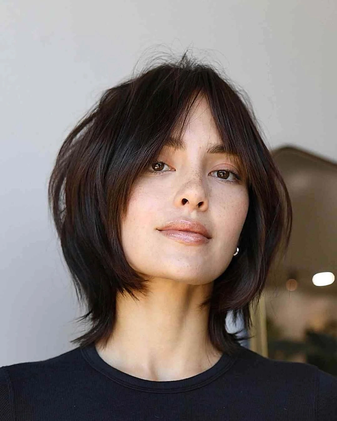 Short dark layered hair with airy center-opening curtain bangs