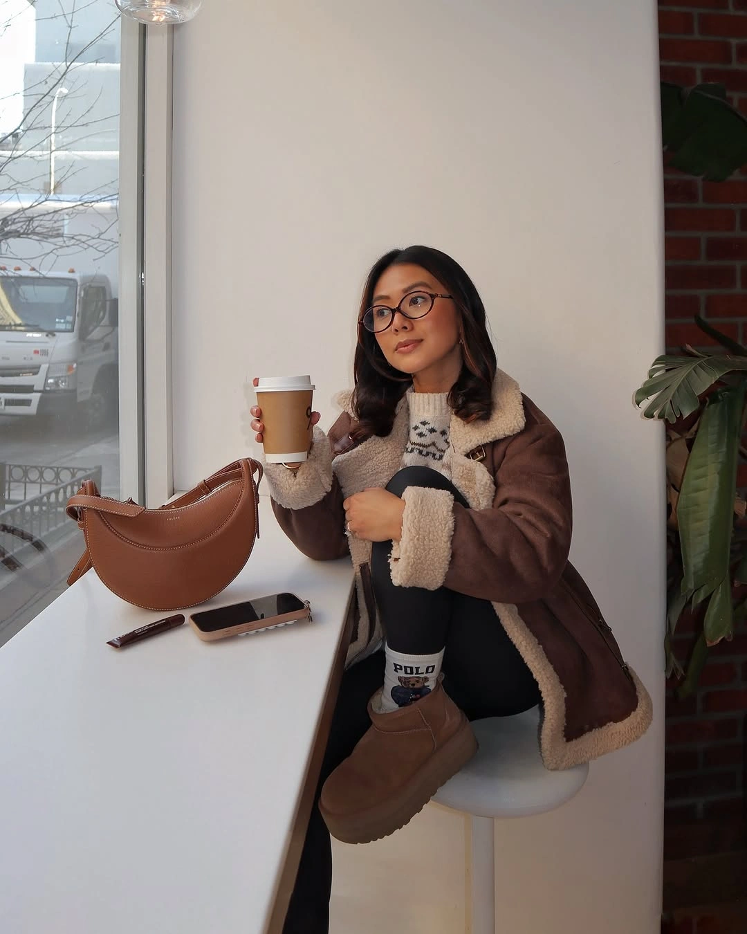 Brown shearling-style coat, cream knit, black layer and tan boots