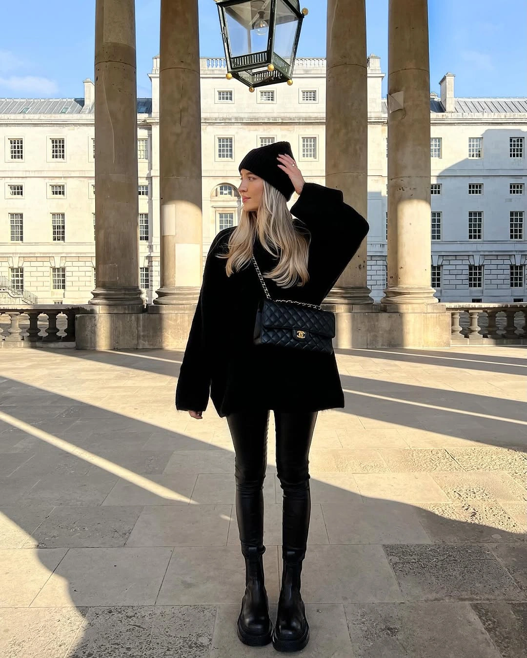 All-black outfit with fuzzy-looking jacket, beanie, bag and boots