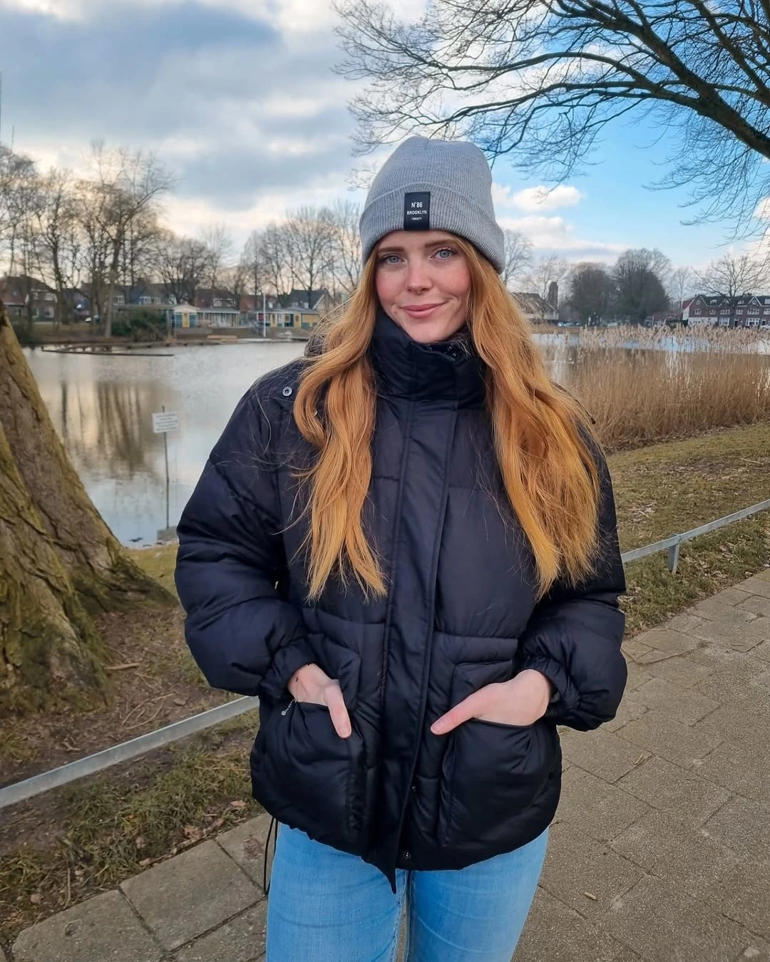 Dark puffy jacket, light blue jeans and gray beanie