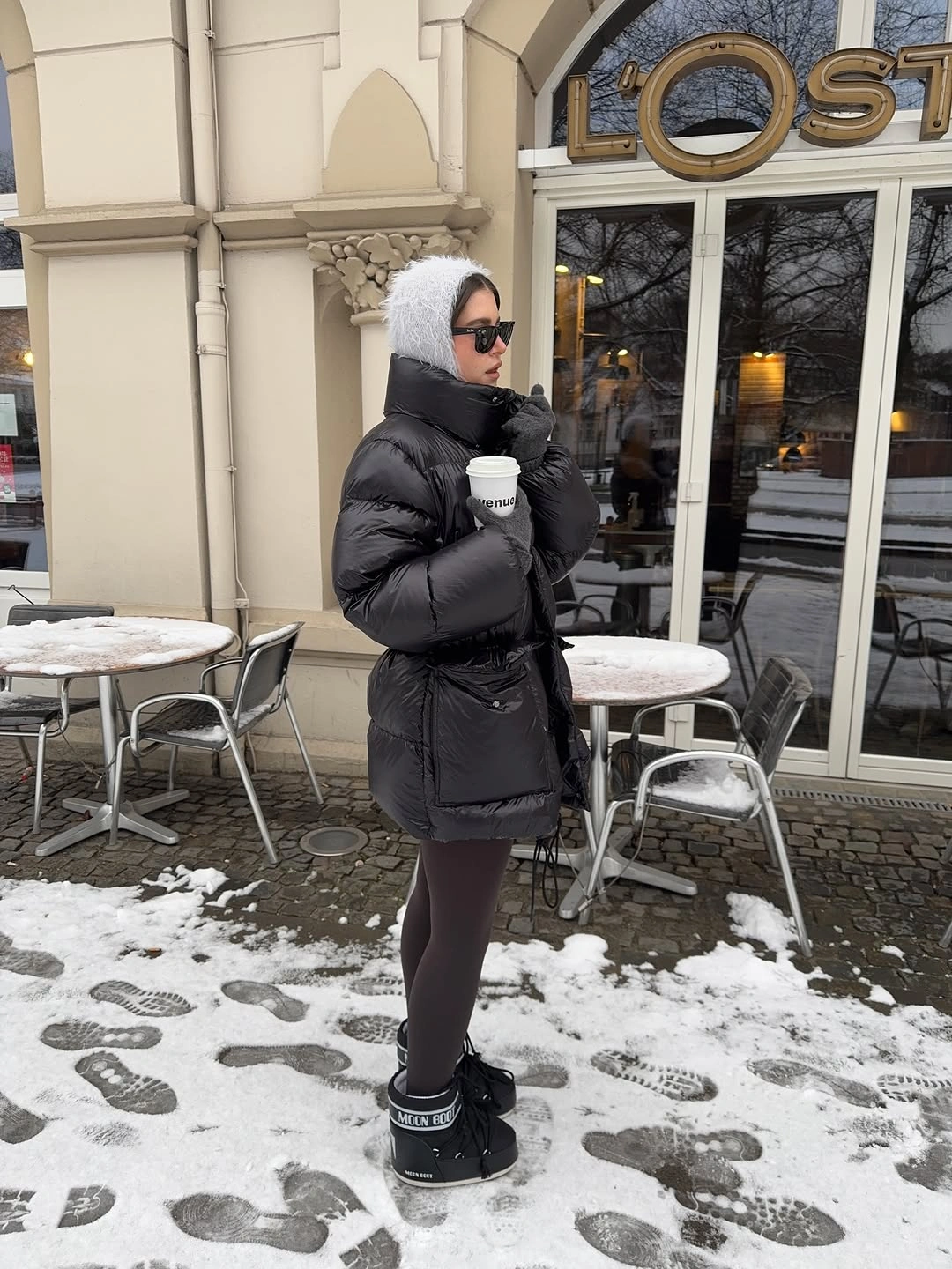 Glossy black puffy jacket, white fuzzy head covering and black boots