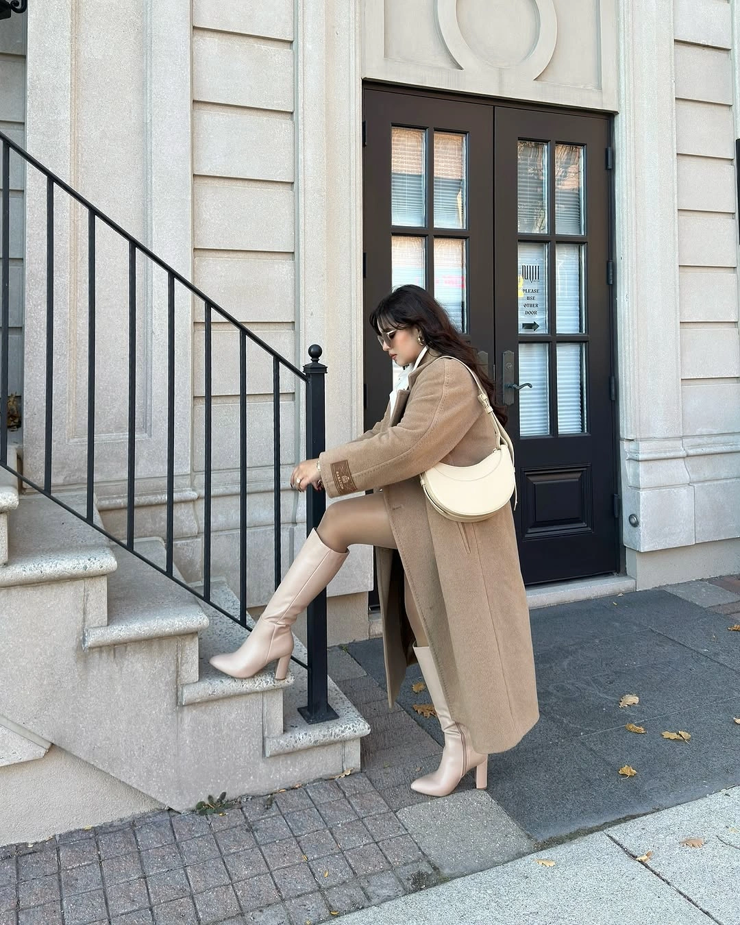 Camel coat, cream knee-high boots, pale shoulder bag