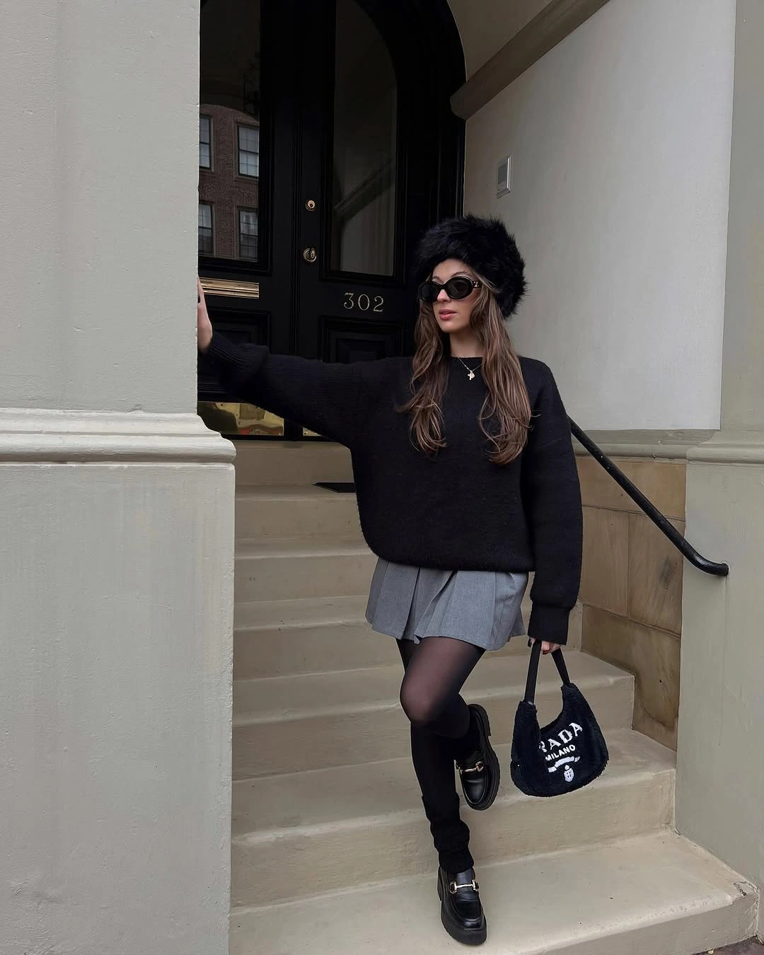 Black oversized sweater, gray pleated mini skirt, dark tights