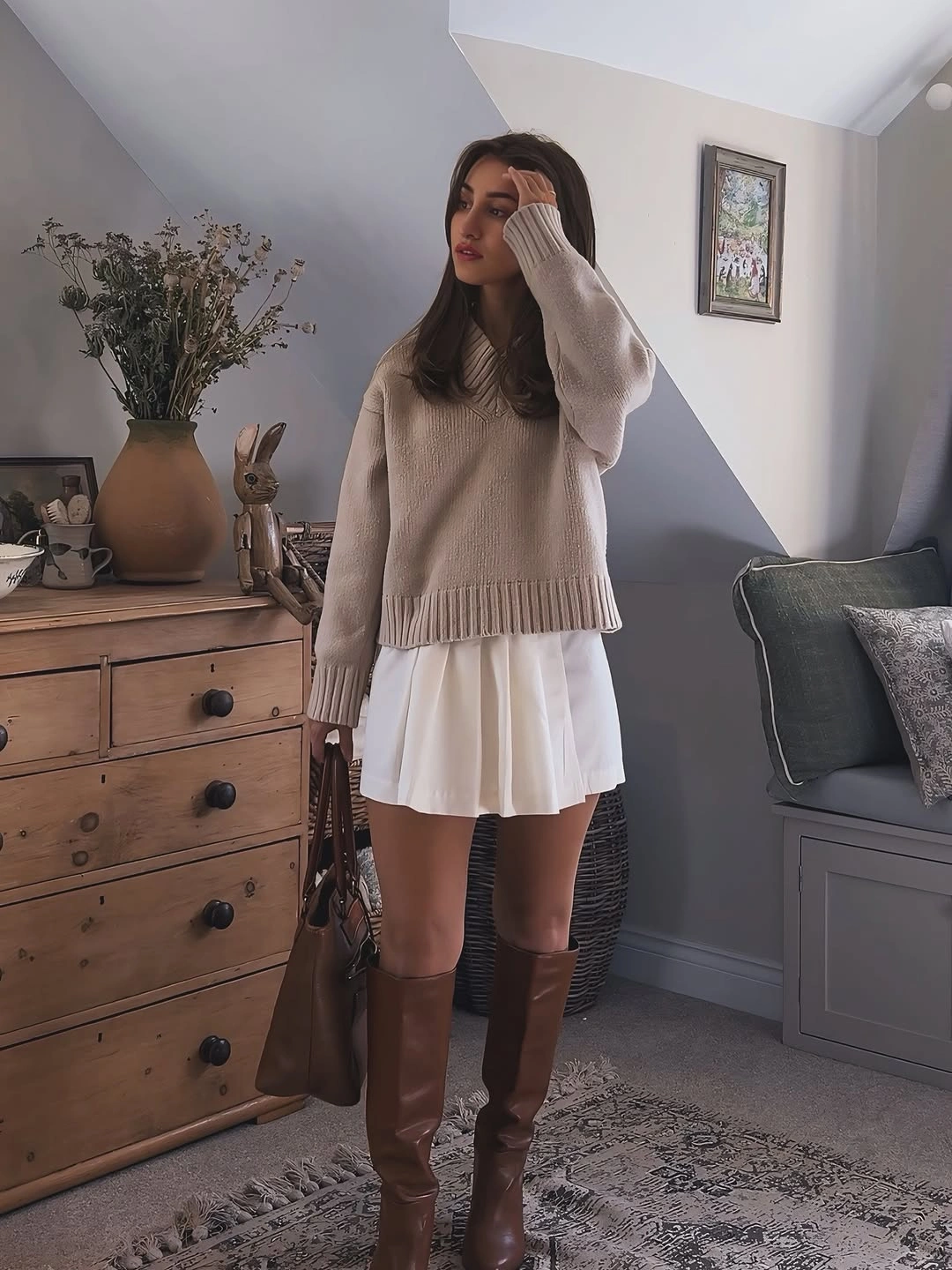 Beige sweater, white pleated mini skirt, brown knee-high boots