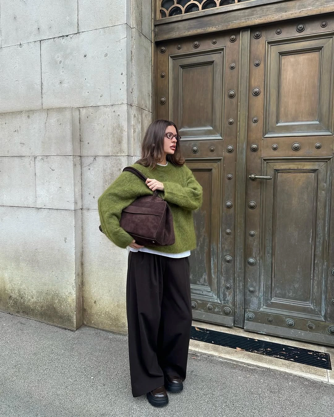 Oversized green sweater with wide dark trousers and brown bag