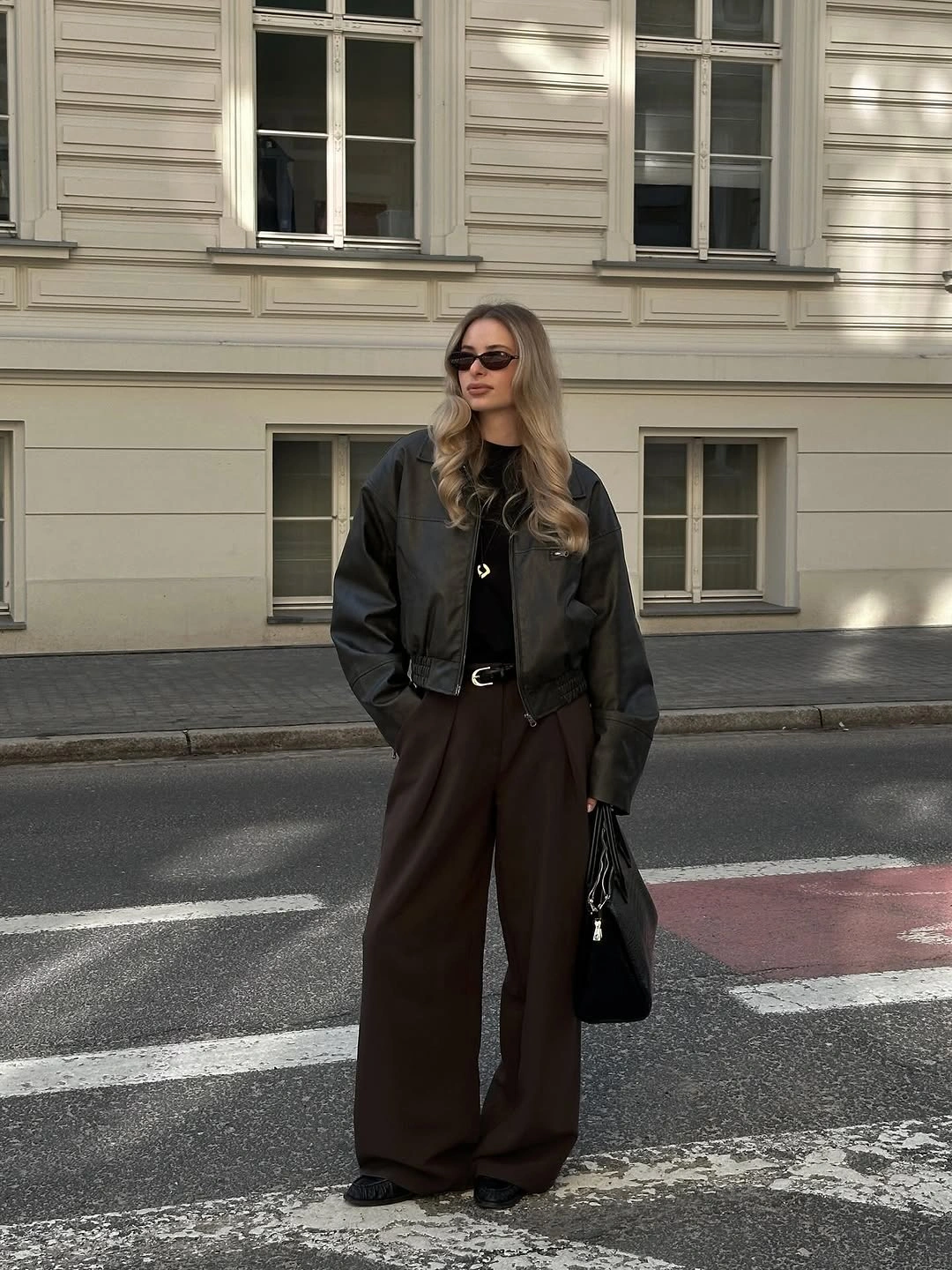 Smooth dark cropped jacket with wide brown trousers and black bag