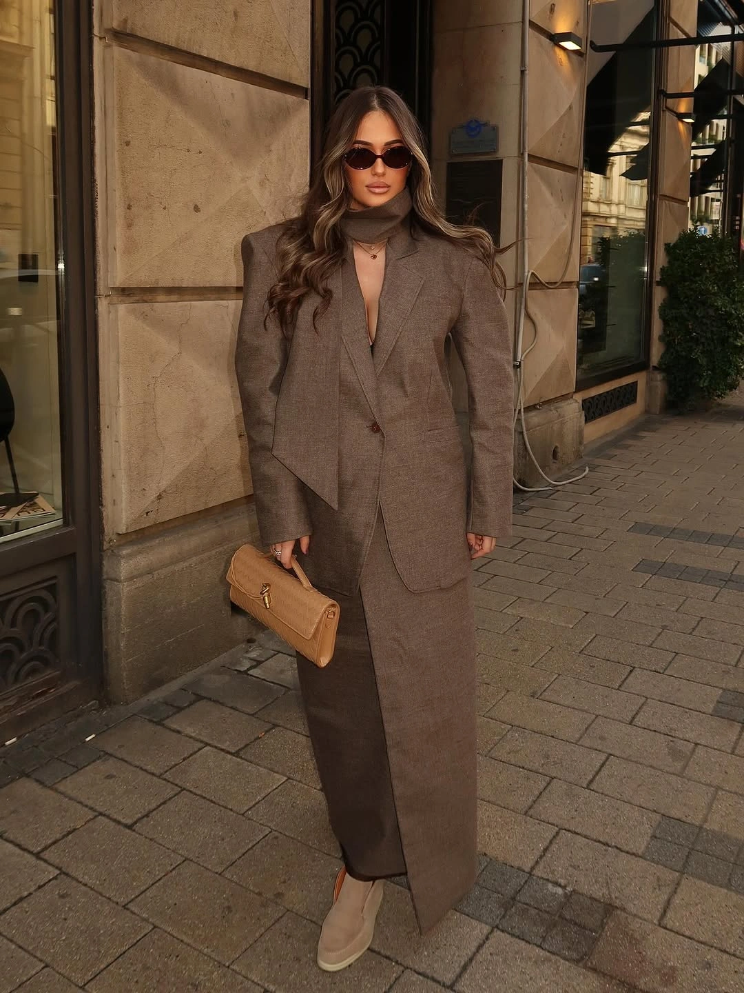Brown tailored blazer with long matching lower line and tan clutch