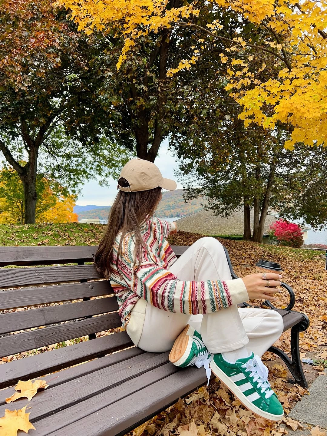 Striped sweater with cream trousers green sneakers and light cap