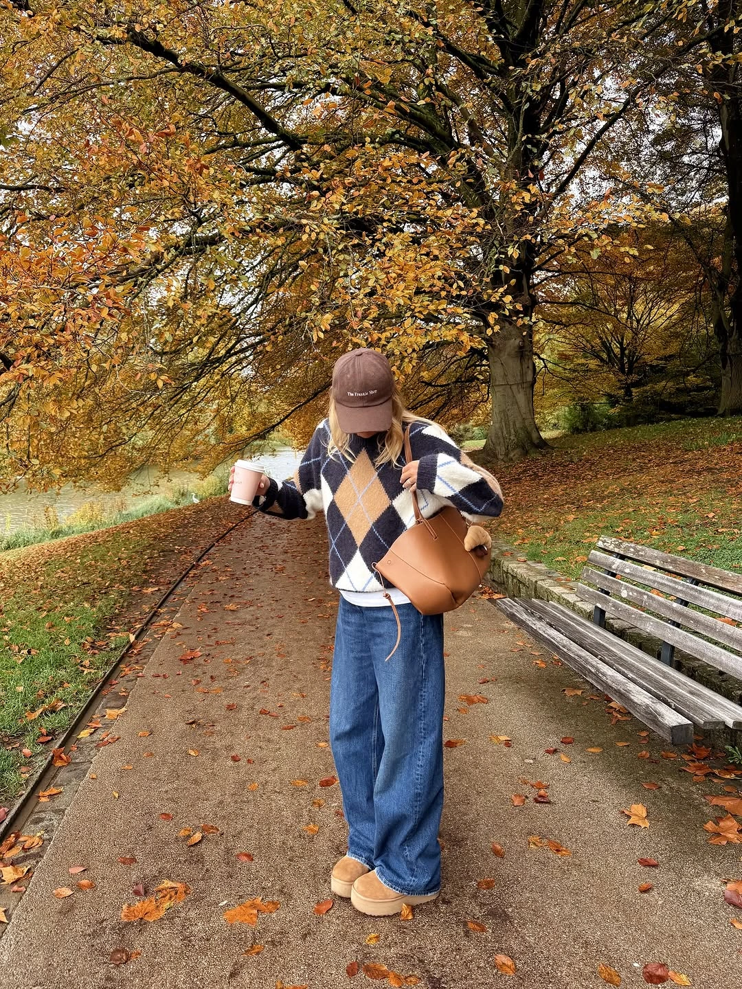 Argyle sweater with loose blue jeans tan bag and brown cap