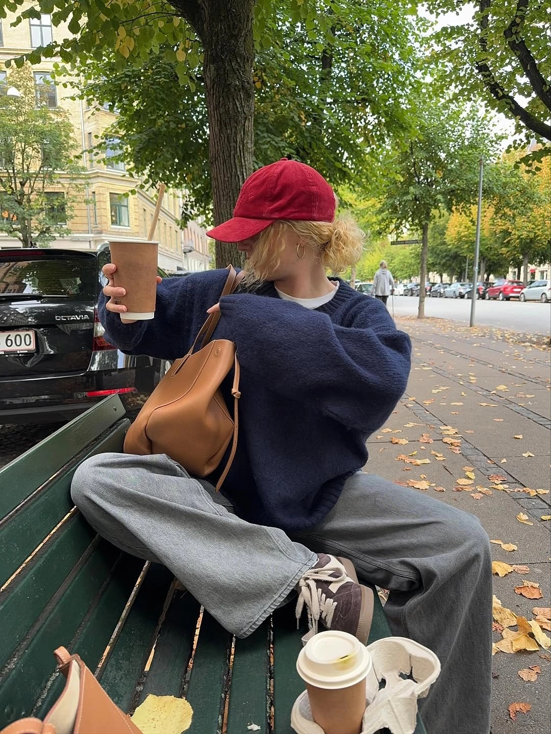 Oversized navy sweater with wide gray trousers red cap and tan bag