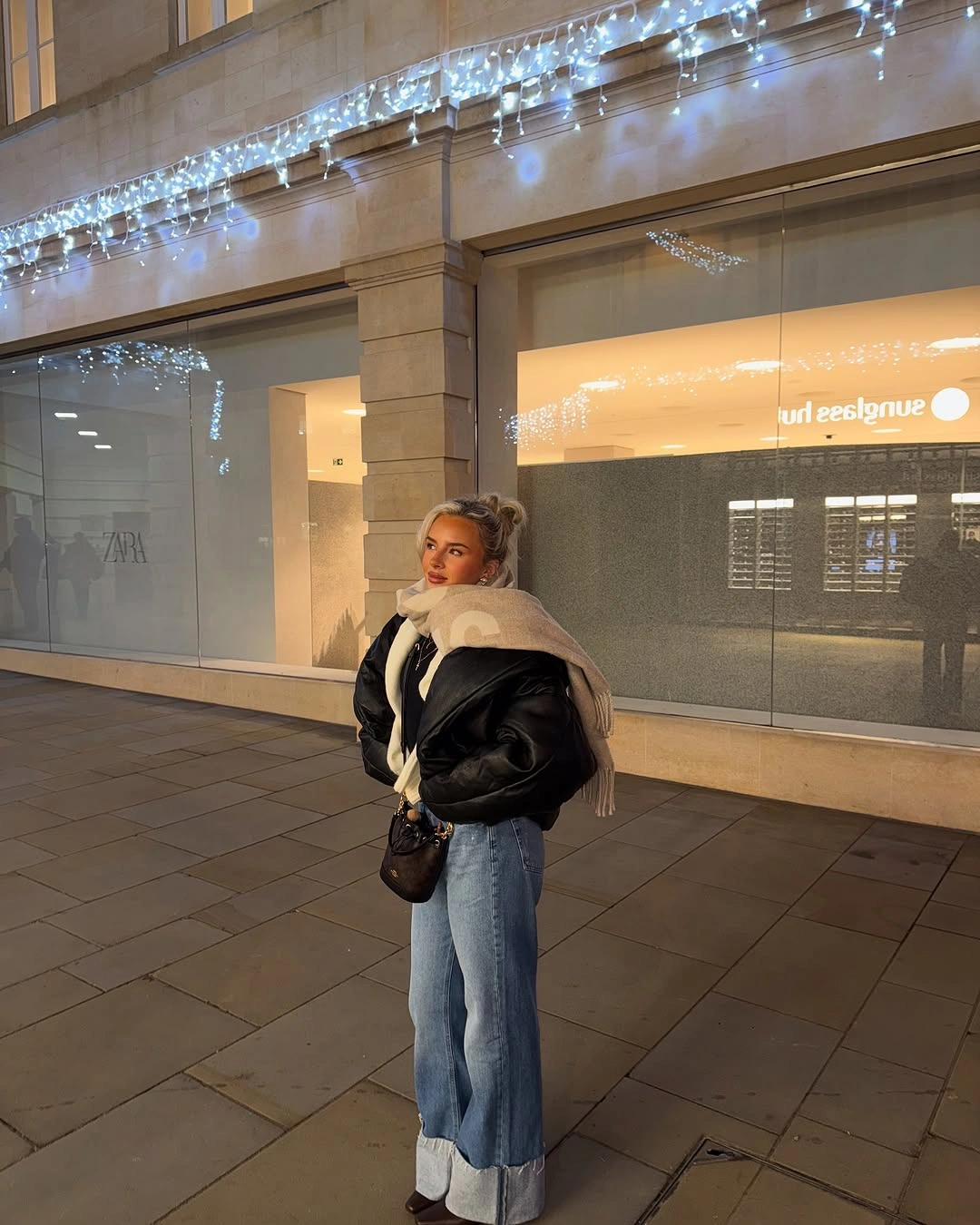 Black cropped jacket with pale scarf and cuffed light jeans