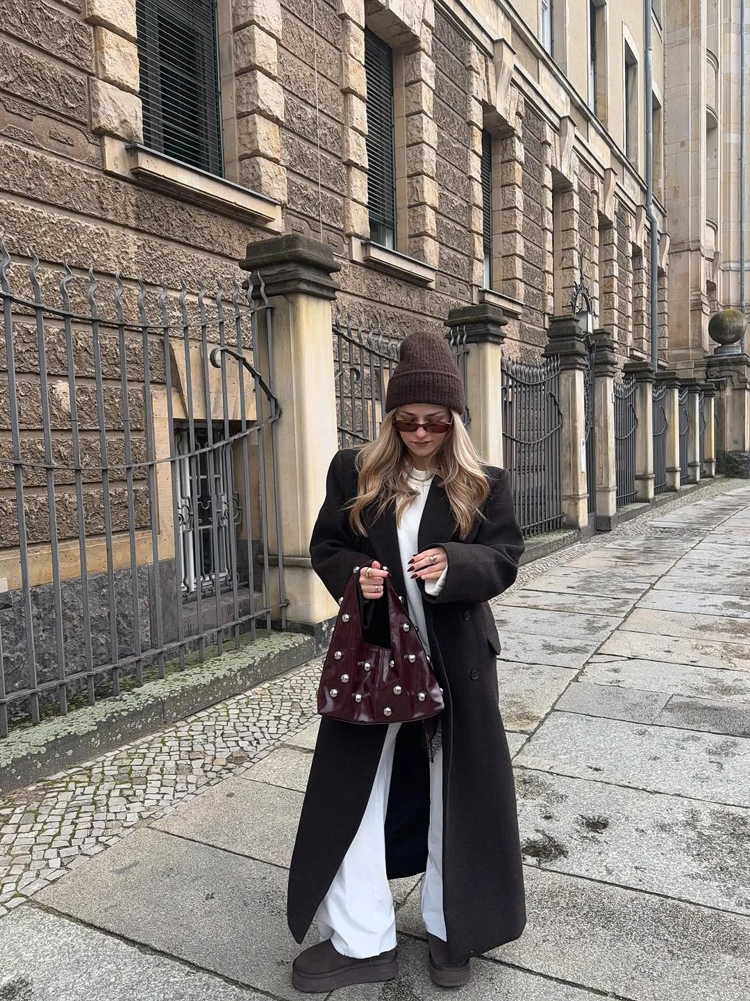 Long black coat with white inner layer and burgundy bag