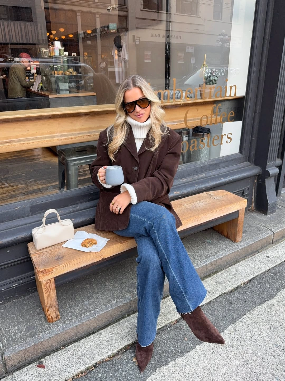 Brown jacket with white turtleneck, blue jeans, and pointed boots