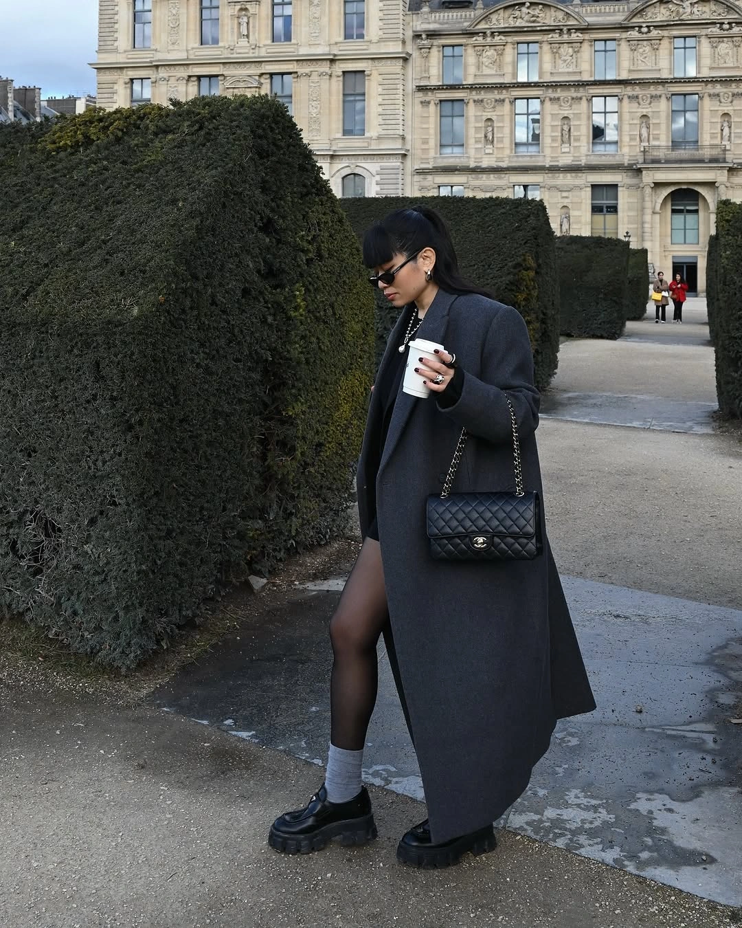 Long charcoal coat with sheer tights, white socks, and loafers