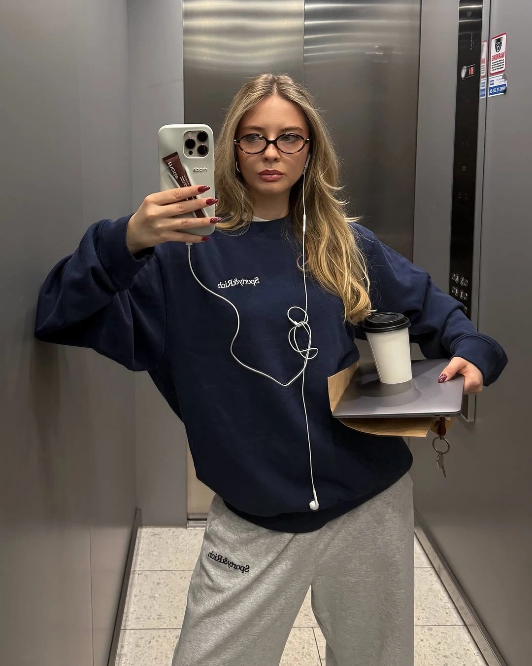 Oversized navy sweatshirt with gray sweatpants and white earphone cord
