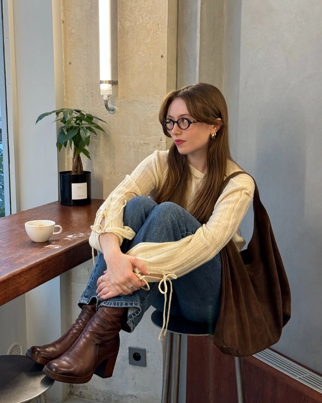 Cream ribbed sweater with jeans, brown boots, and large bag