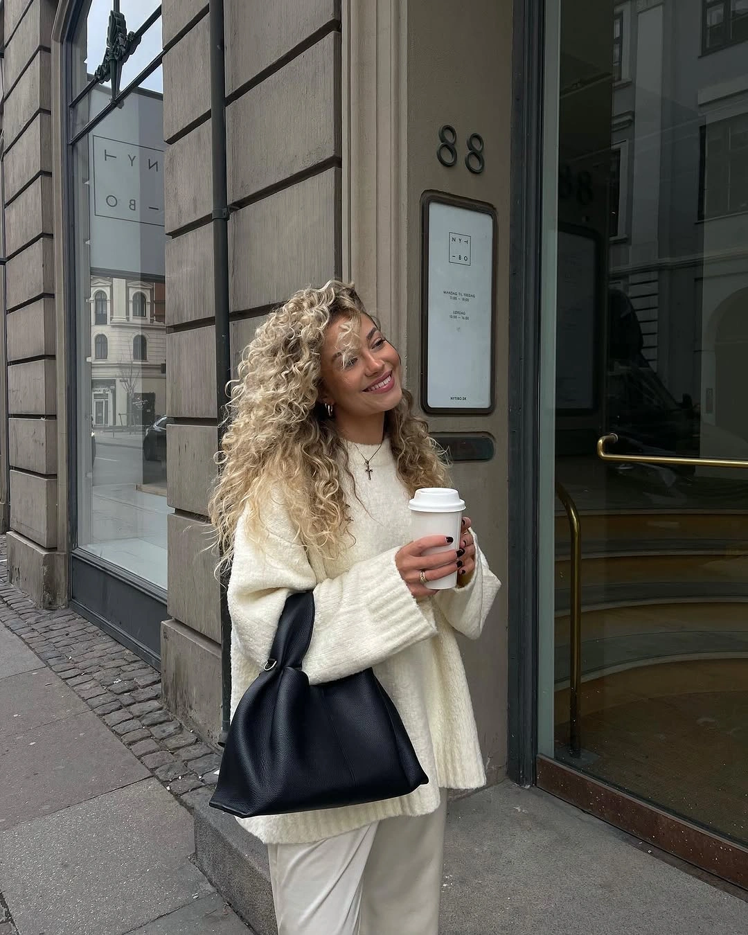 Oversized cream sweater with off-white pants and black shoulder bag