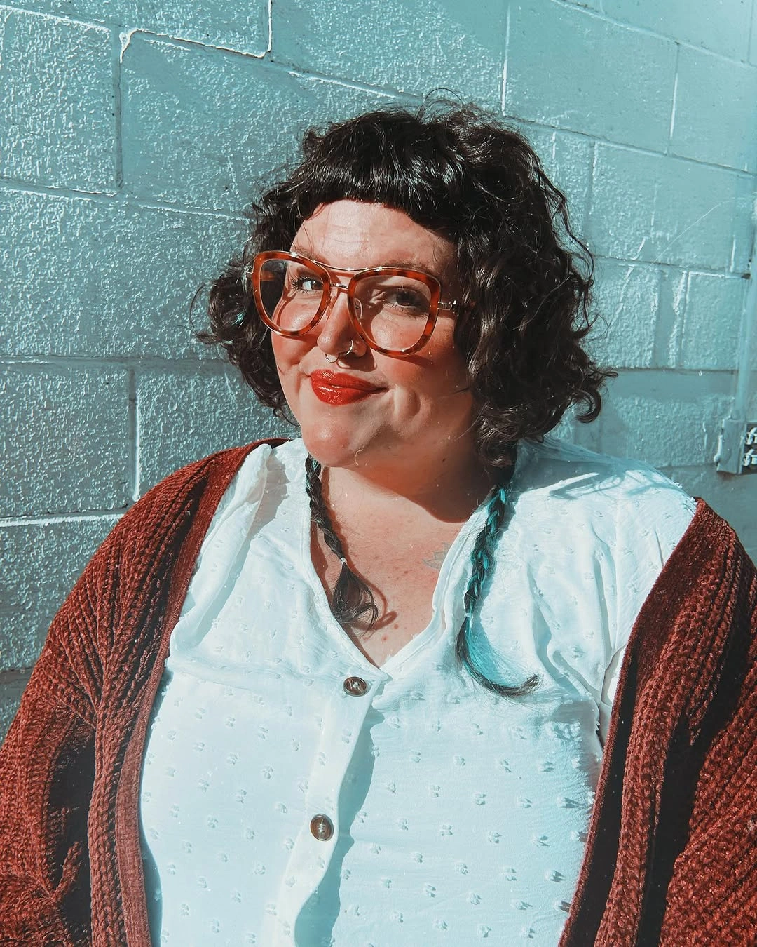 Rounded curly bob with micro bangs and orange glasses