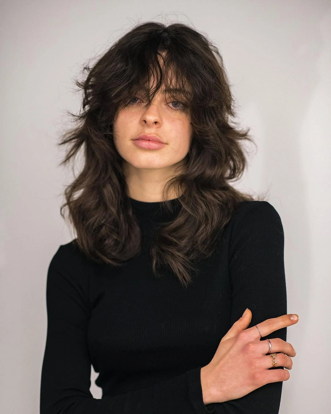Dark shoulder-length shag with parted bangs and flared side layers
