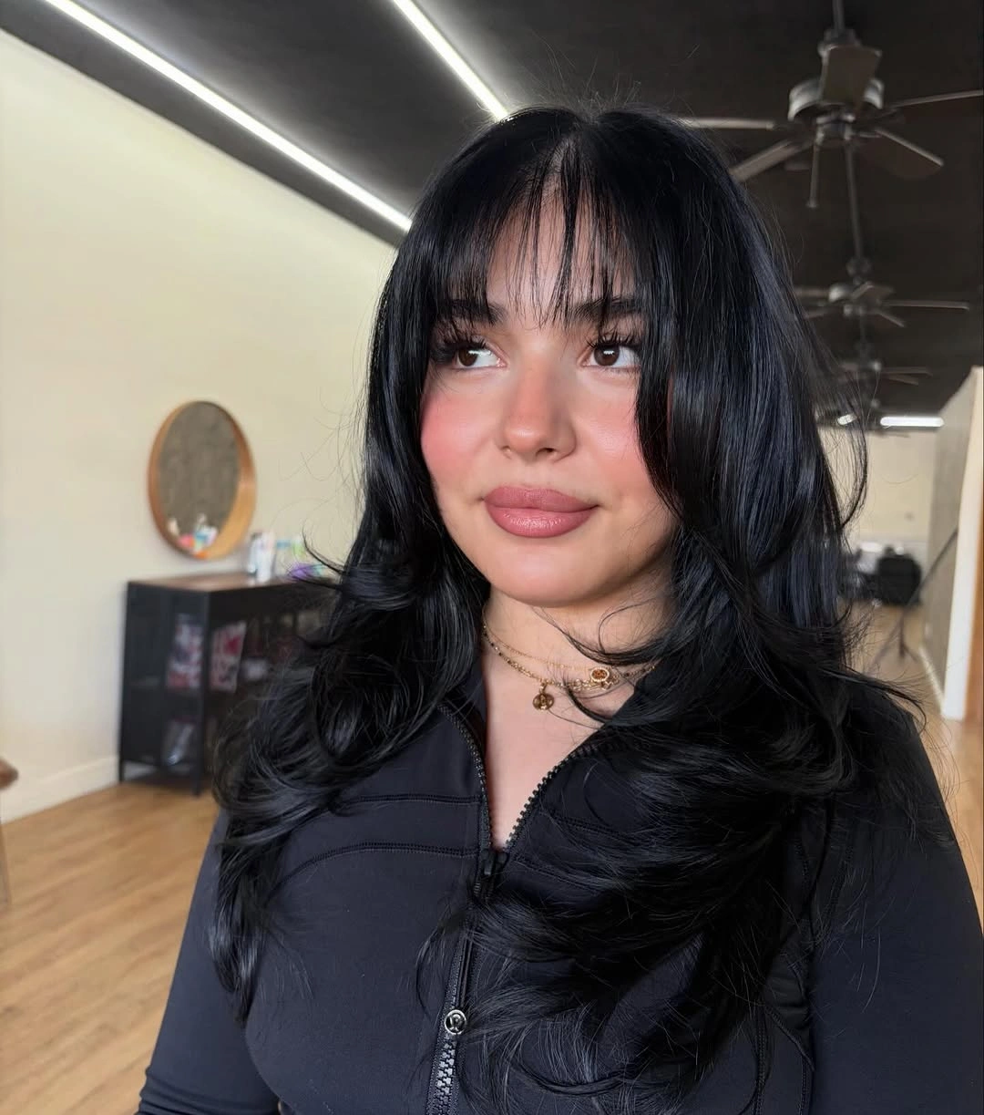 Long black layered haircut with full wispy bangs and curled ends