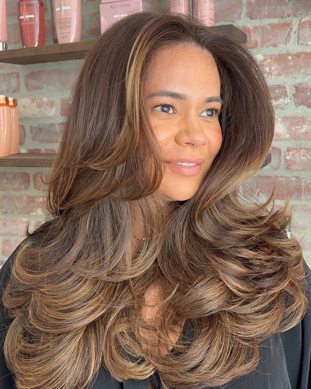Long brunette haircut with lighter face frame and curled layered ends