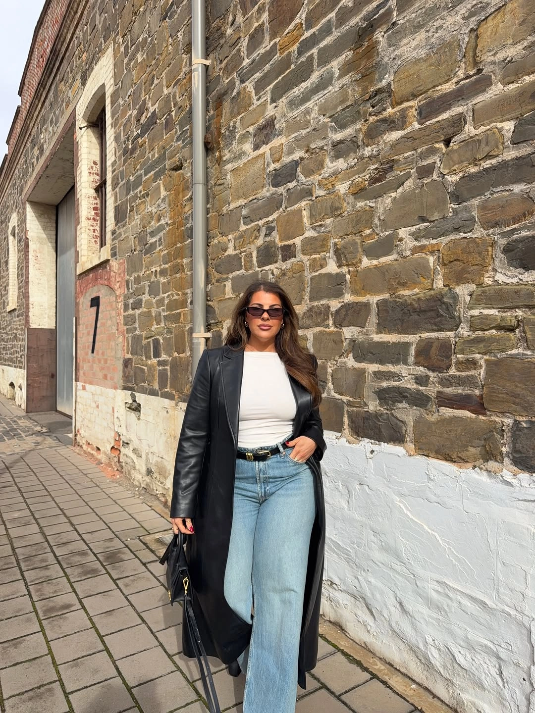 Long black coat with white top and light jeans