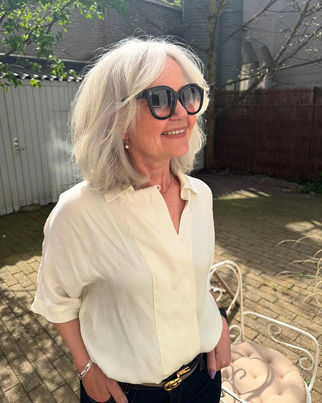 Silver shoulder-length layered haircut with feathered ends and center part
