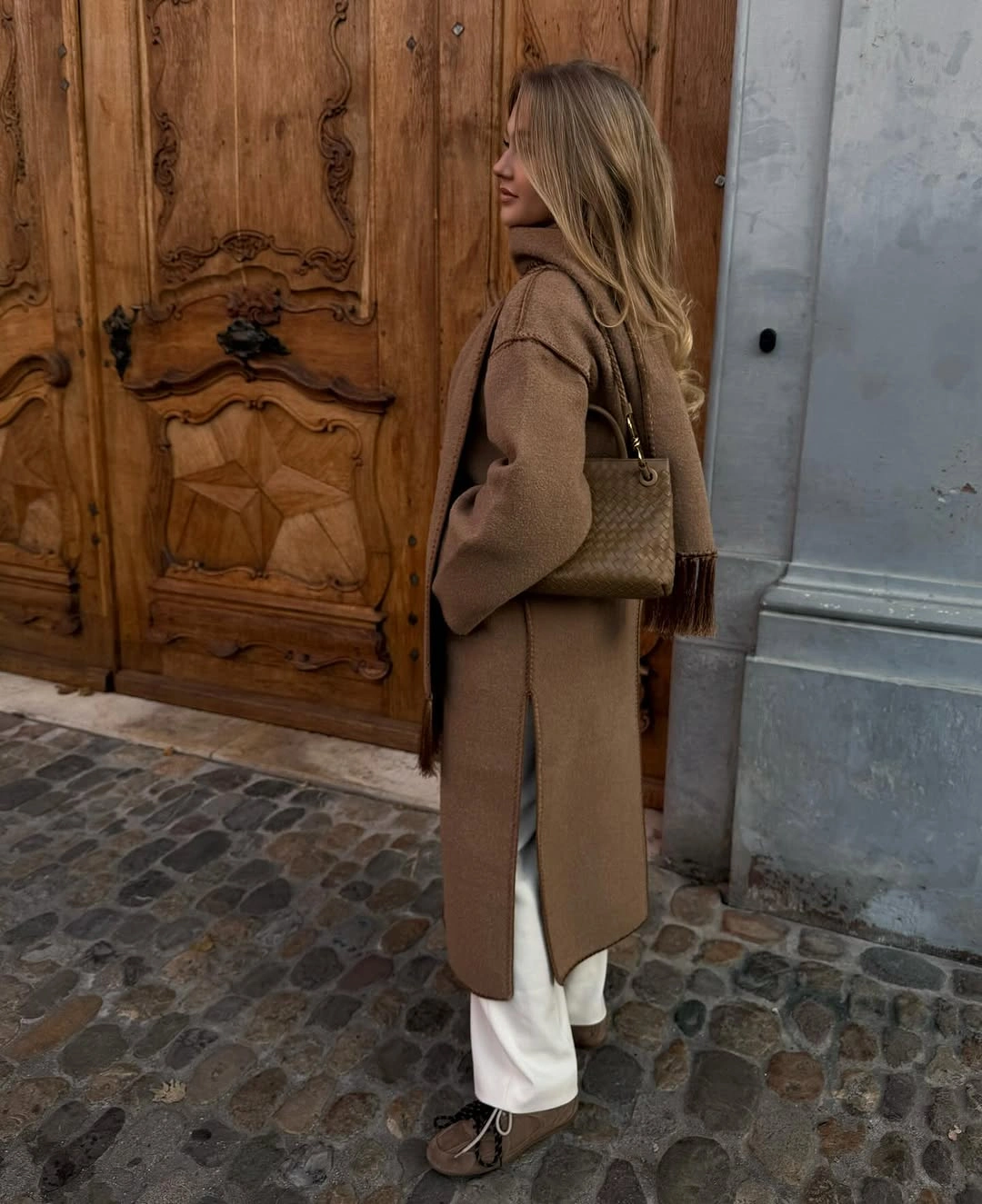Side view of camel coat with white trousers