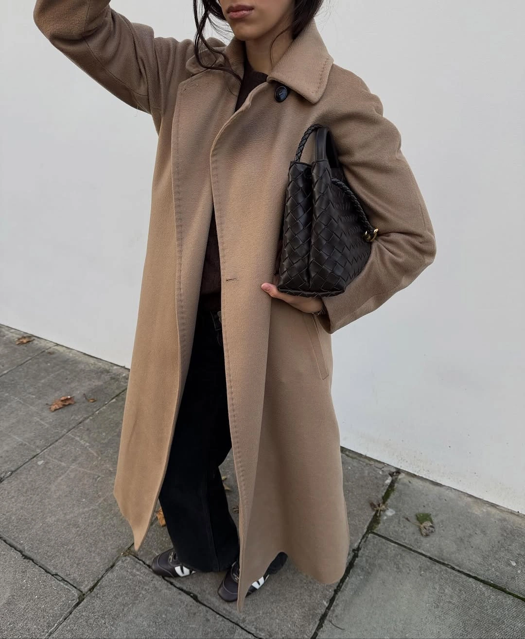 Camel coat with woven black bag and striped sneakers