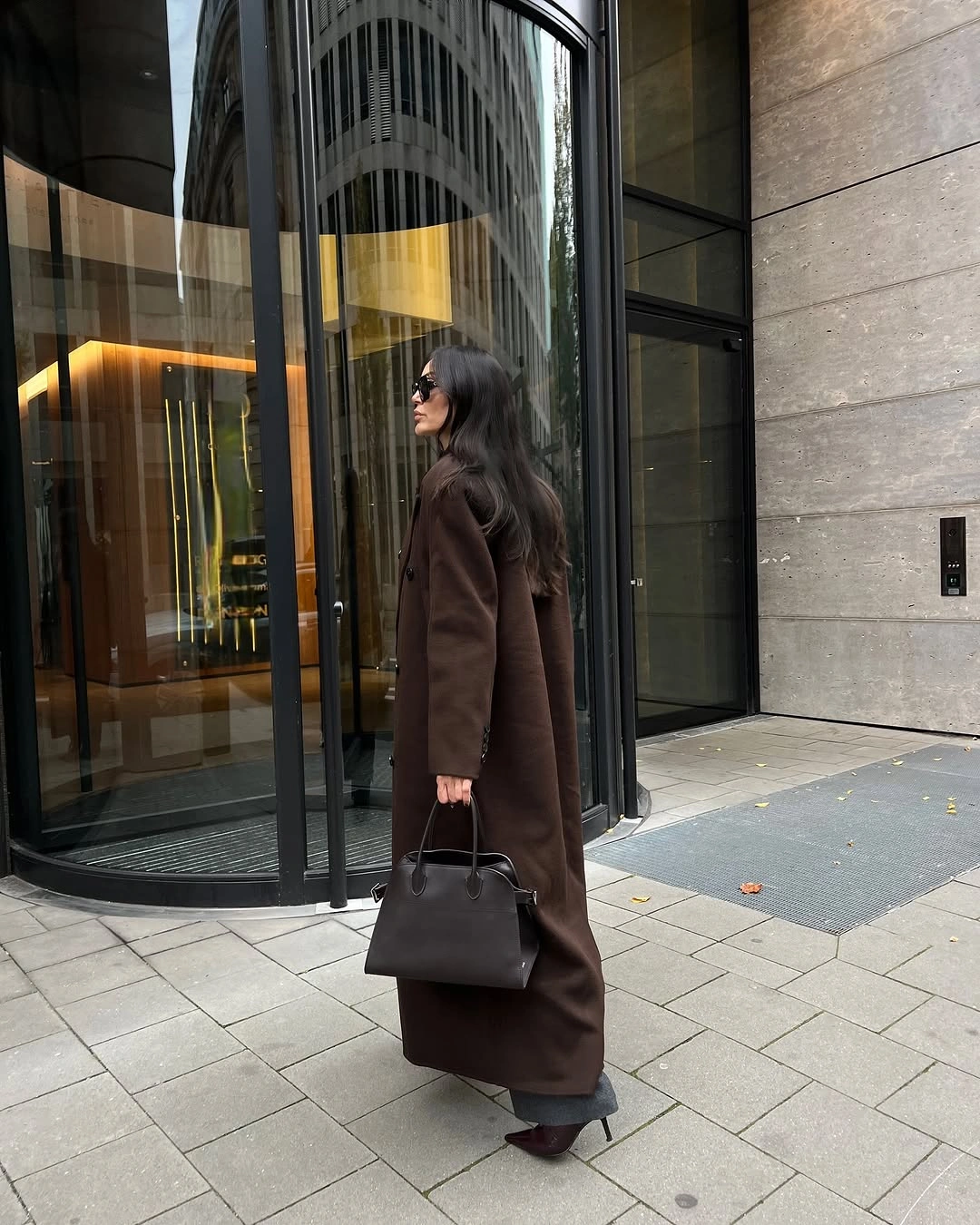 Long dark brown coat with structured black handbag