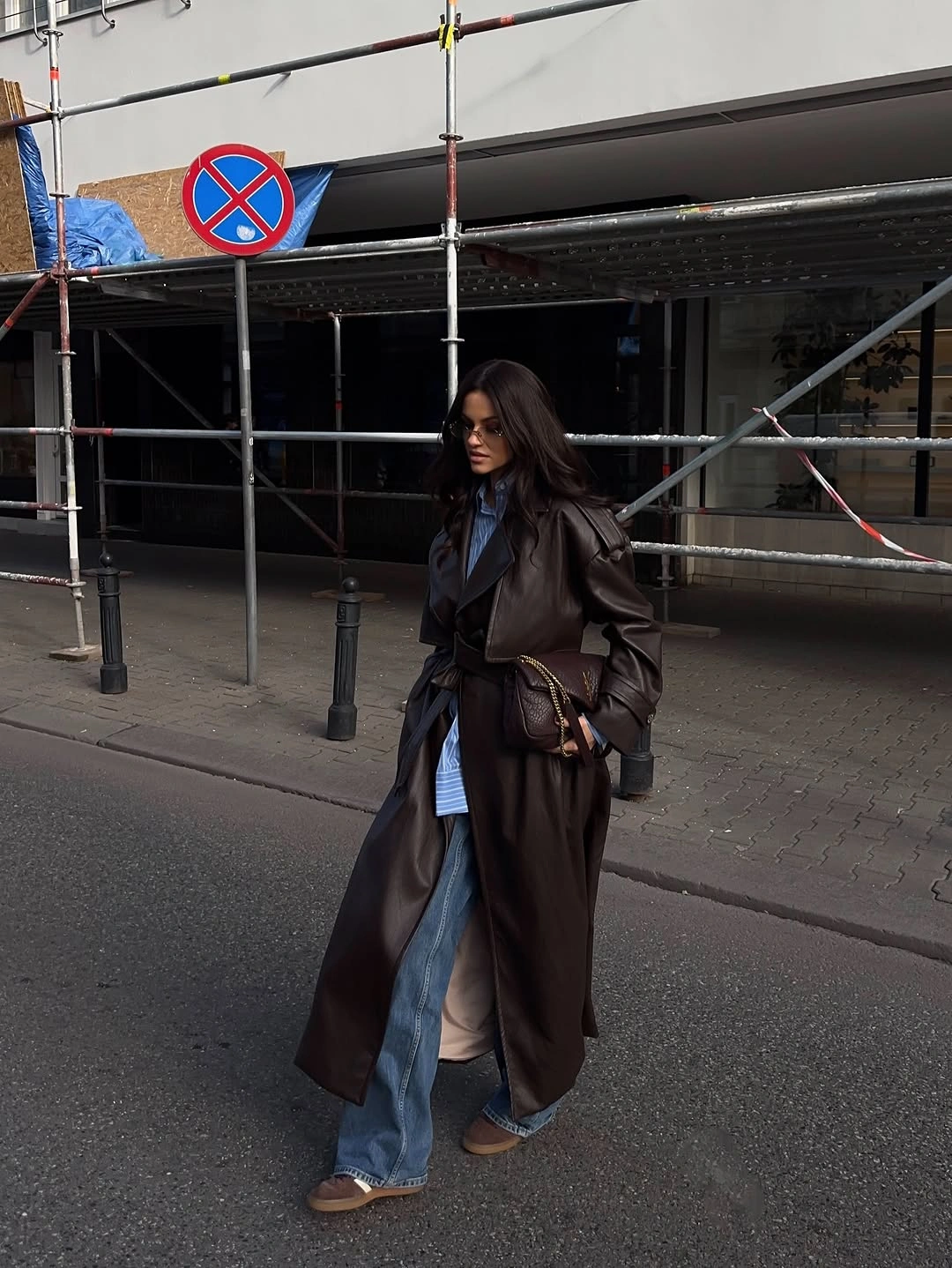 Long glossy dark trench with denim and tan shoes