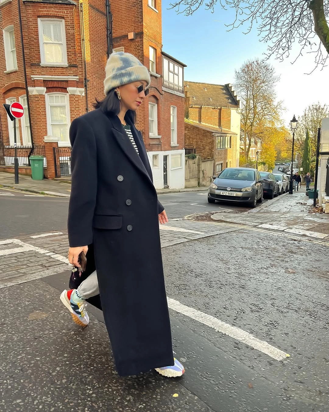 Long navy coat with pale knit hat and sneakers