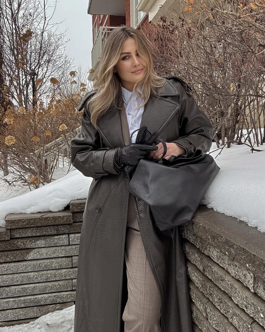 Textured gray-brown coat with black tote beside snow