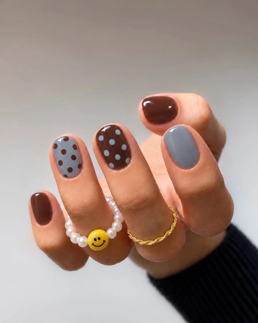 Short rounded brown and gray nails with pale dotted accents