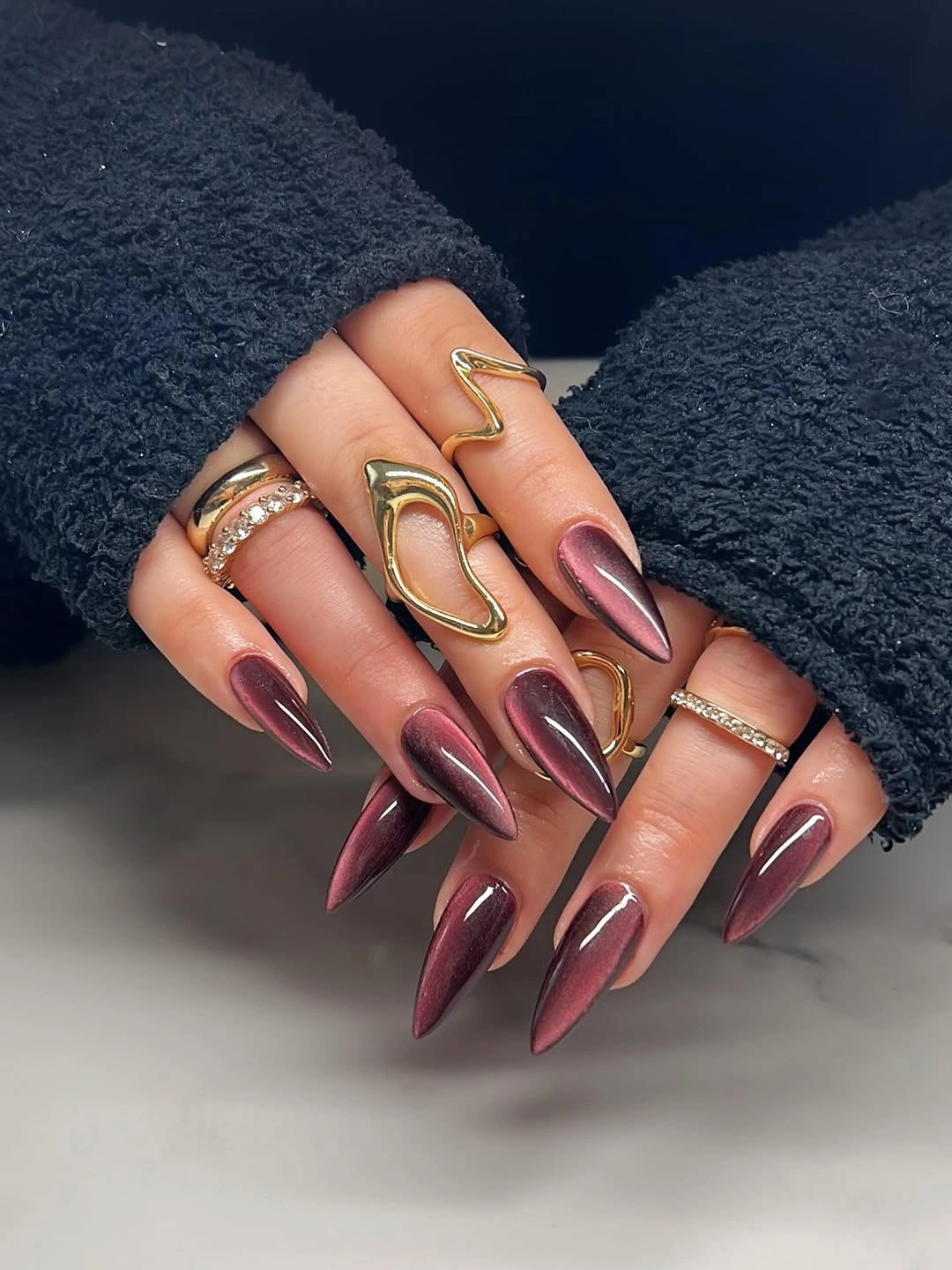 Long stiletto burgundy nails with metallic-looking reflective streaks