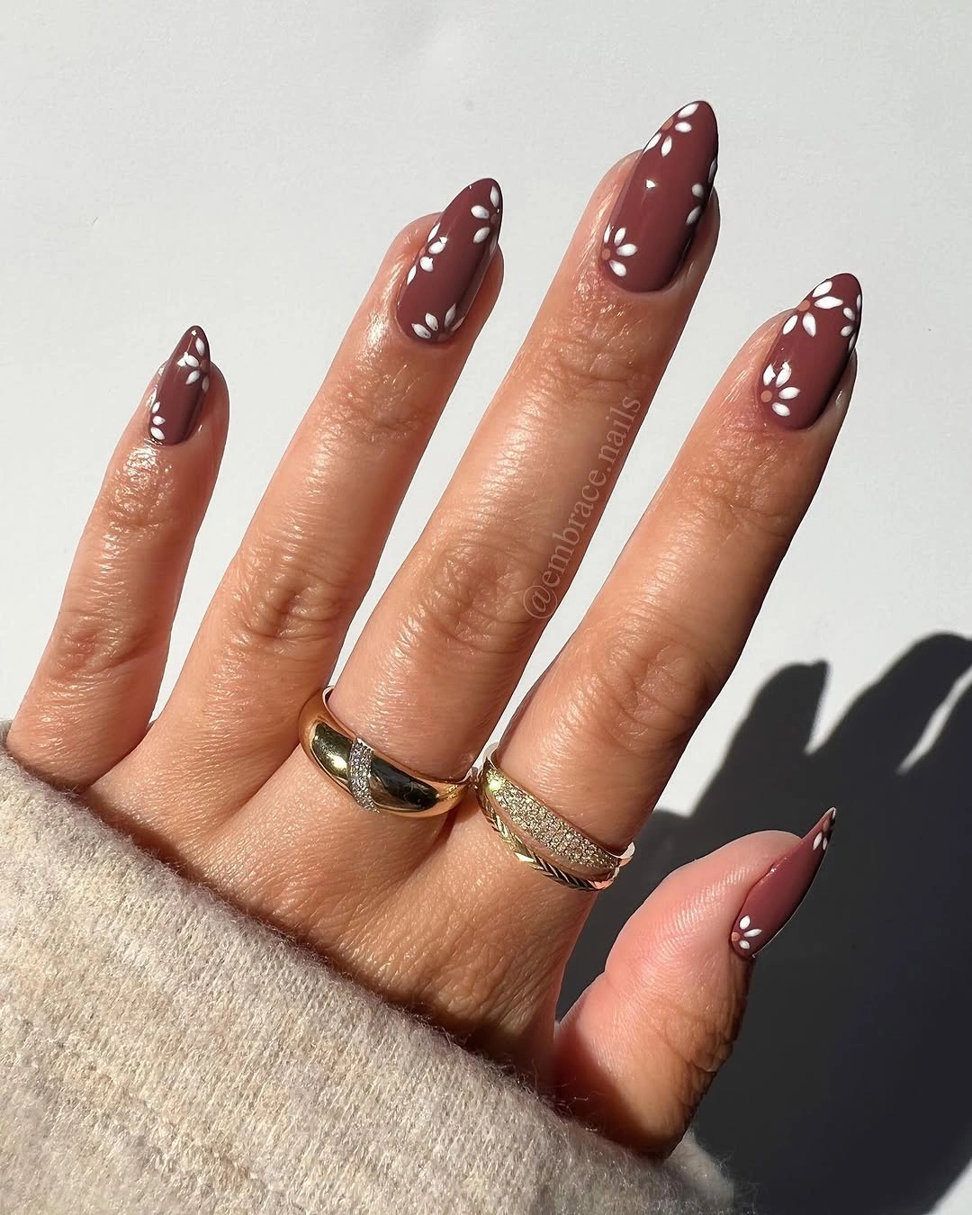 Brown almond nails with white flowers and dot clusters