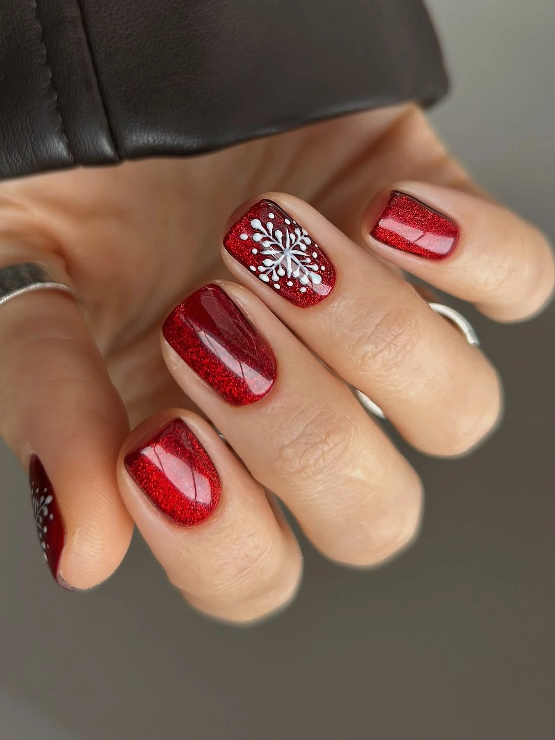 Short red glitter nails with white snowflake accent