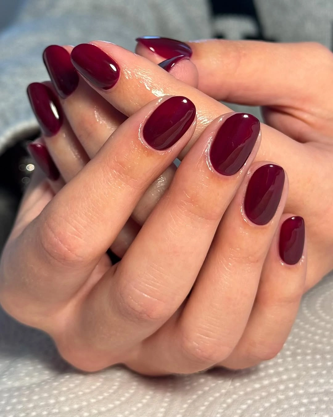 Short glossy burgundy nails in close hand pose
