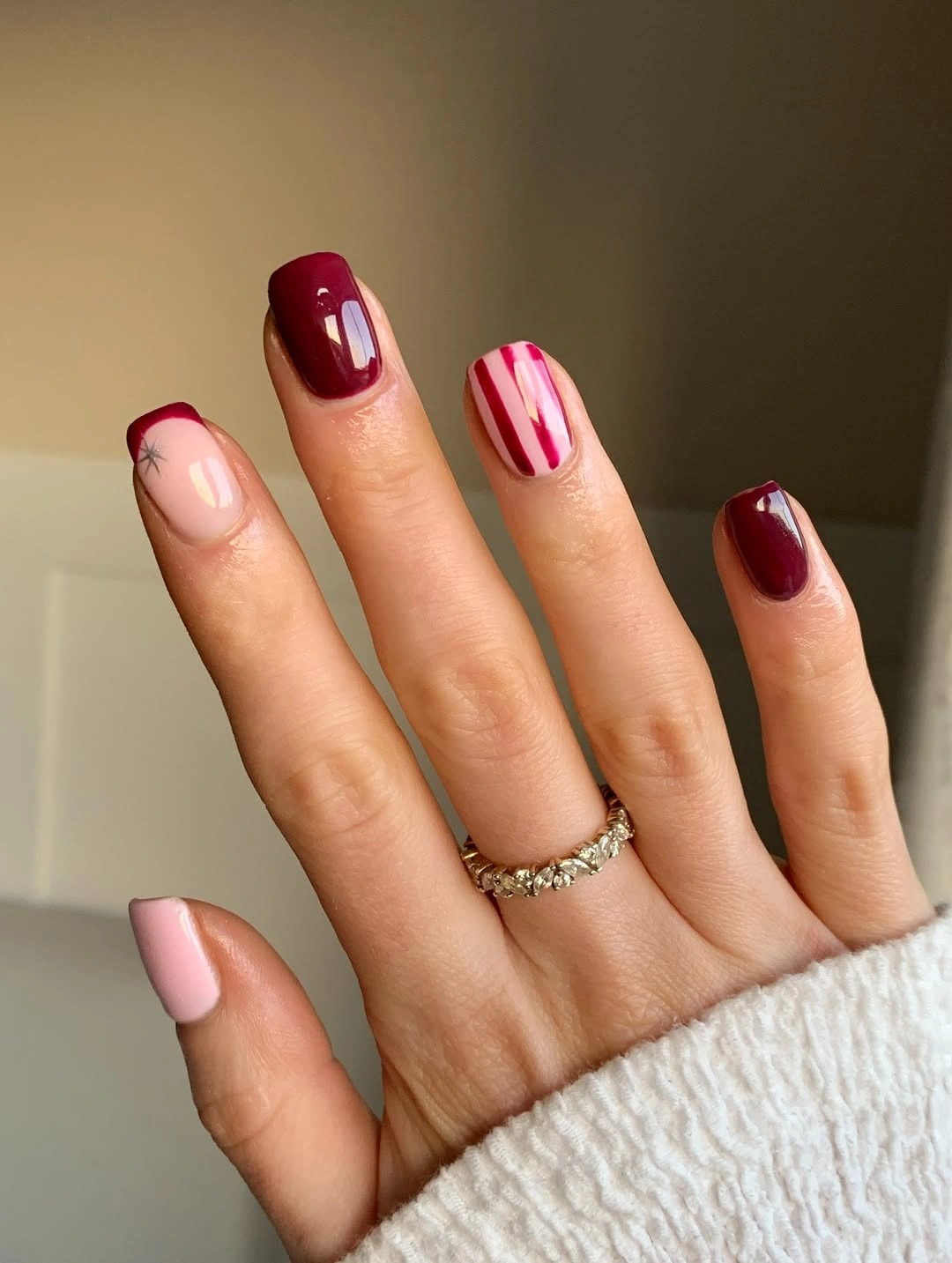 Short pink and burgundy nails with striped accent