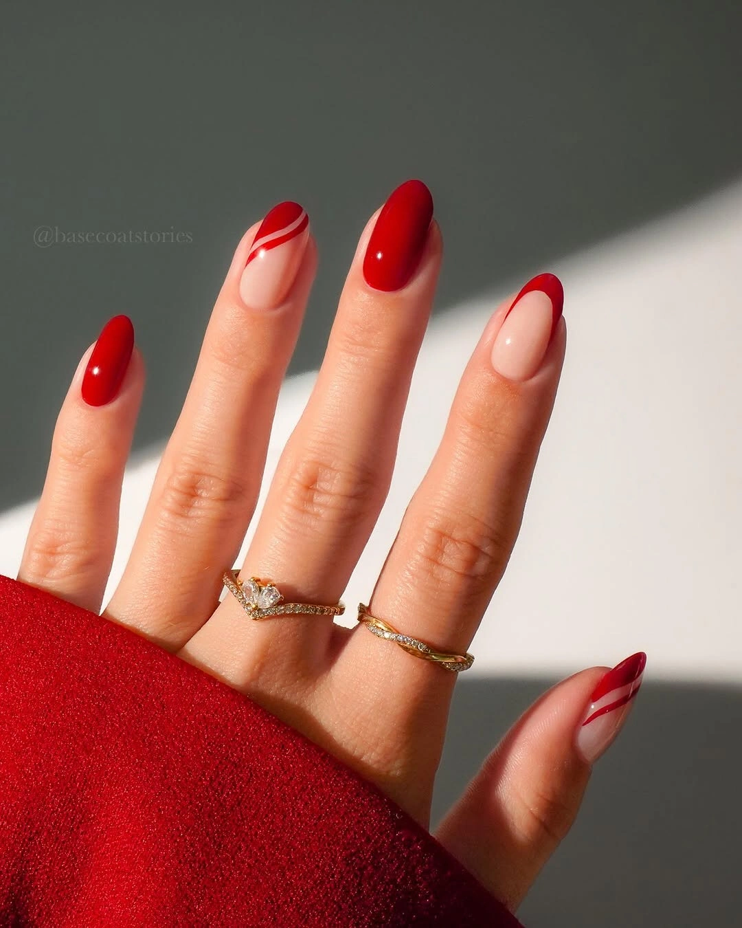 Almond red nails with nude accents and curved white lines