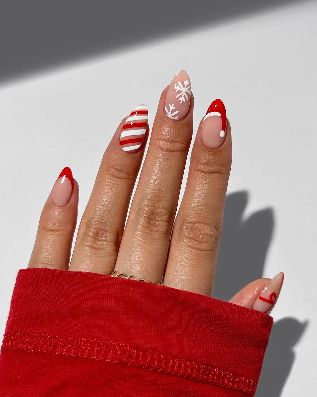 Almond nails with red tips, stripes, dots and snowflake art