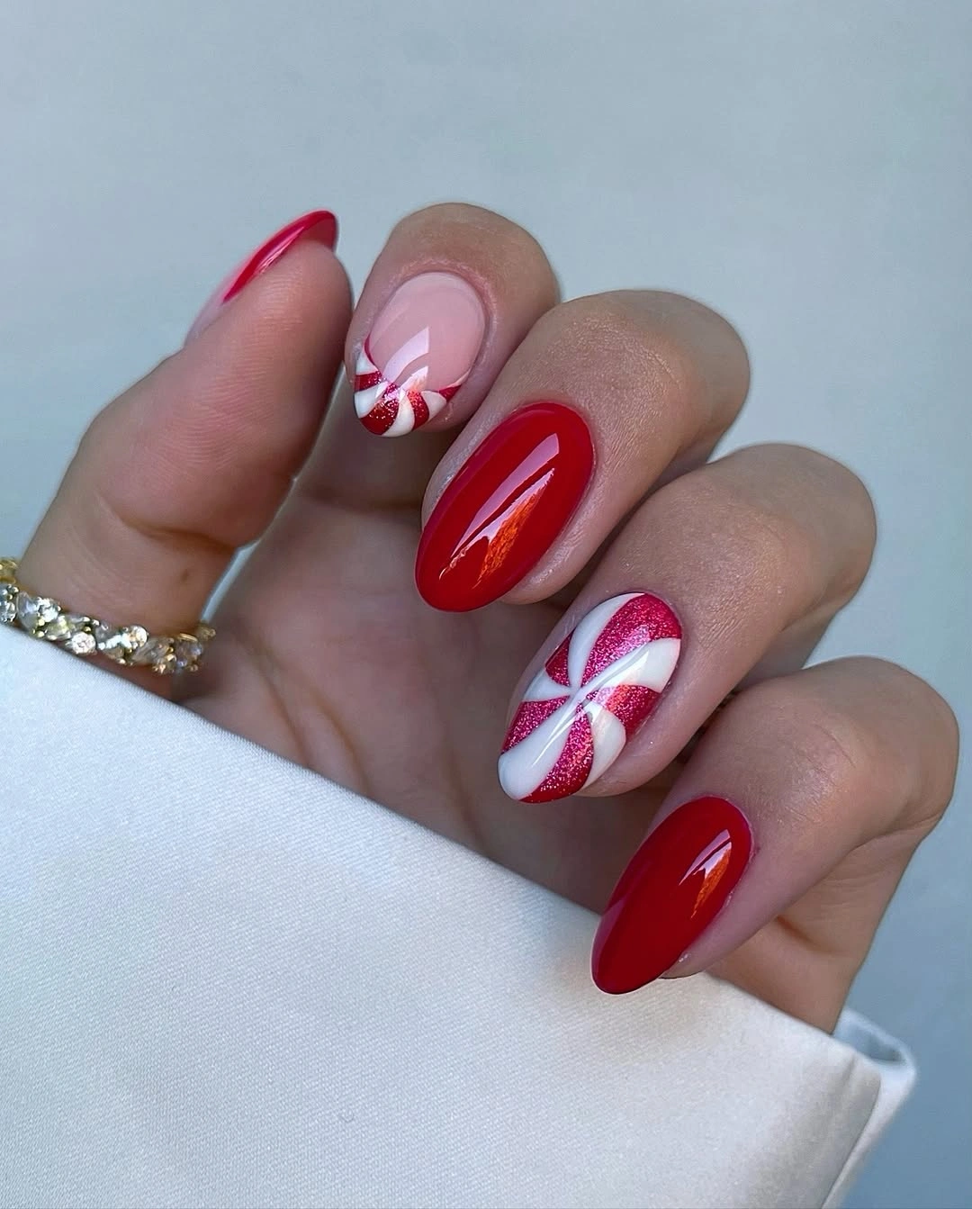 Almond red nails with candy cane accents and pink bases
