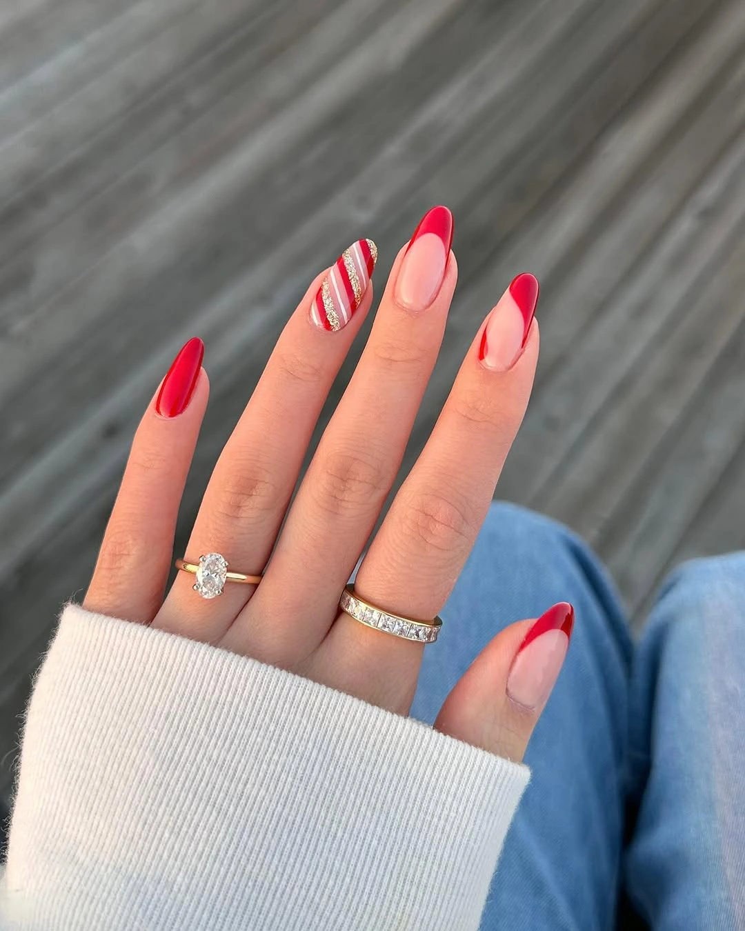 Almond red nails with nude tips and striped accent nail