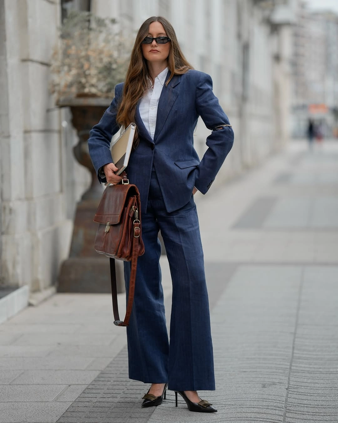 Blue suit white shirt brown bag folder and pointed black shoes