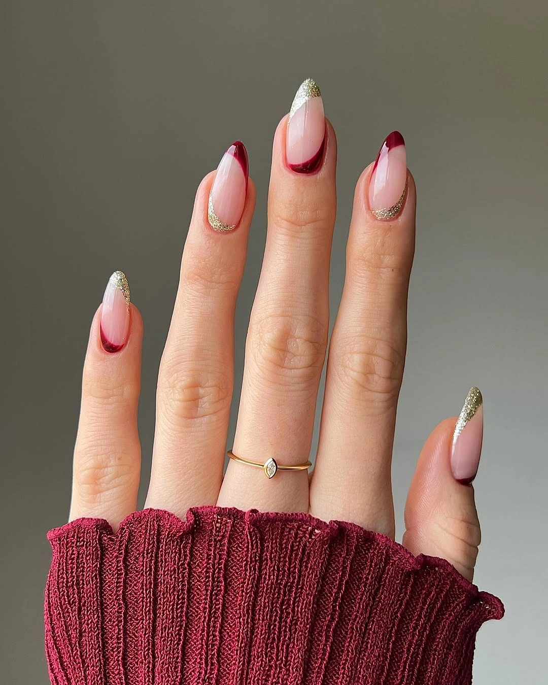 Almond nails with deep red French tips and gold curves