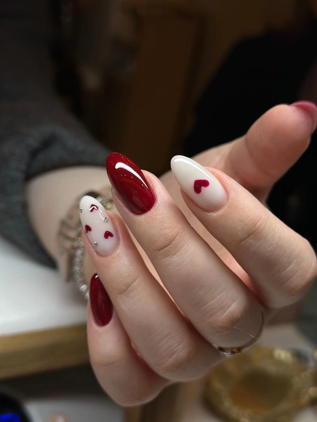 Short deep red nails with white accents and small hearts