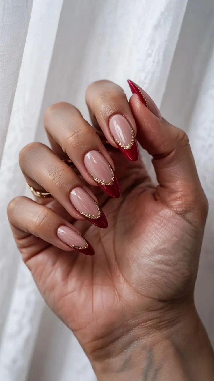 Long pointed nails with red French edges and gold borders