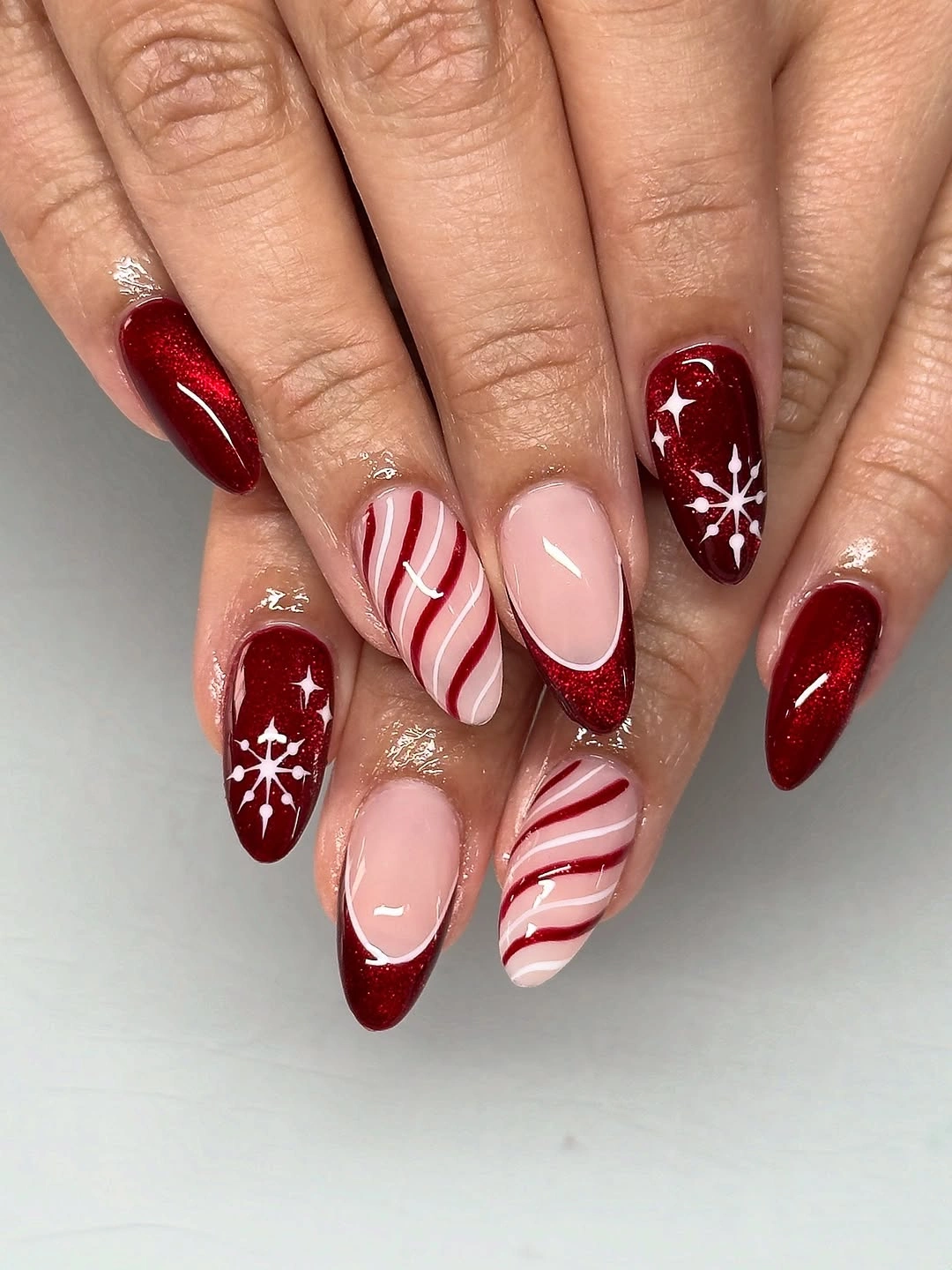 Almond red glitter nails with candy stripes and white snowflakes